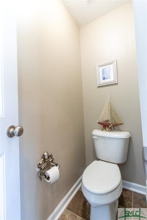 126 NE Owens St, Ludowici, GA 31316 - bathroom with a textured ceiling, baseboards, toilet, and tile patterned flooring