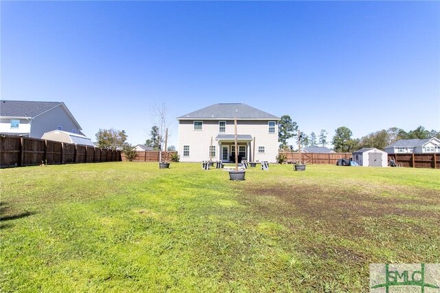 126 NE Owens St, Ludowici, GA 31316 - back of property with an outdoor structure, a fenced backyard, a lawn, and a shed