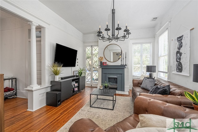 2210 Bull St, Savannah, GA 31401 - living room featuring visible vents, a chandelier, a fireplace with flush hearth, wood finished floors, and ornate columns