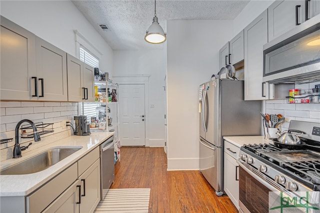 2210 Bull St, Savannah, GA 31401 - kitchen featuring light wood finished floors, gray cabinets, a sink, stainless steel appliances, and light countertops