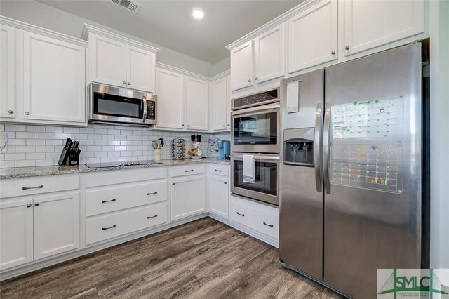 55 Saddlebrush Rd, Ellabell, GA 31308 - kitchen featuring dark wood-type flooring, tasteful backsplash, white cabinetry, visible vents, and appliances with stainless steel finishes
