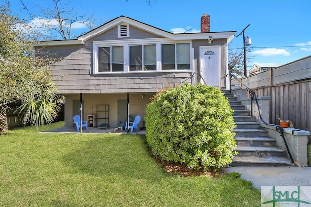 rear view of house featuring a yard, a patio, a chimney, and fence