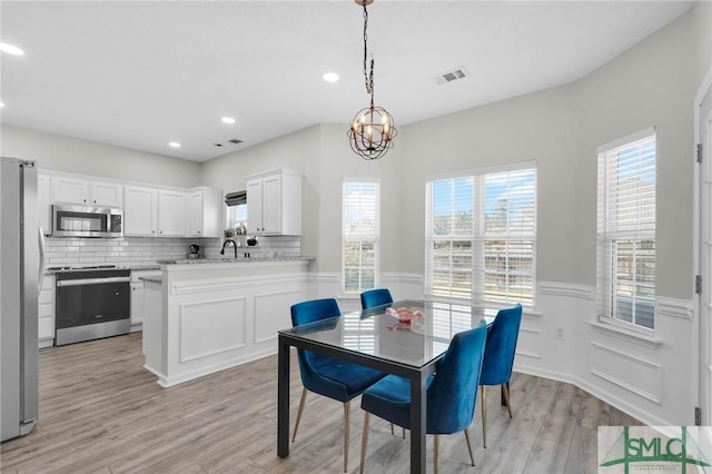 dining area with visible vents, recessed lighting, light wood-style floors, wainscoting, and a notable chandelier