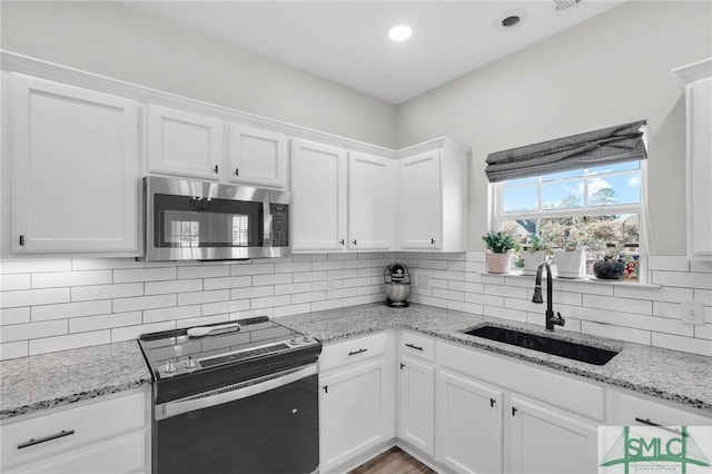 kitchen with a sink, decorative backsplash, range with electric cooktop, white cabinets, and stainless steel microwave