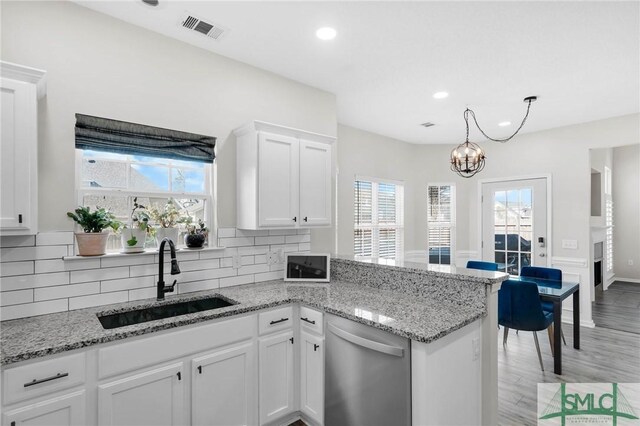 kitchen featuring visible vents, a sink, tasteful backsplash, stainless steel dishwasher, and white cabinetry
