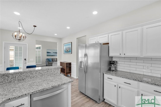 kitchen with light stone counters, decorative backsplash, appliances with stainless steel finishes, and white cabinets