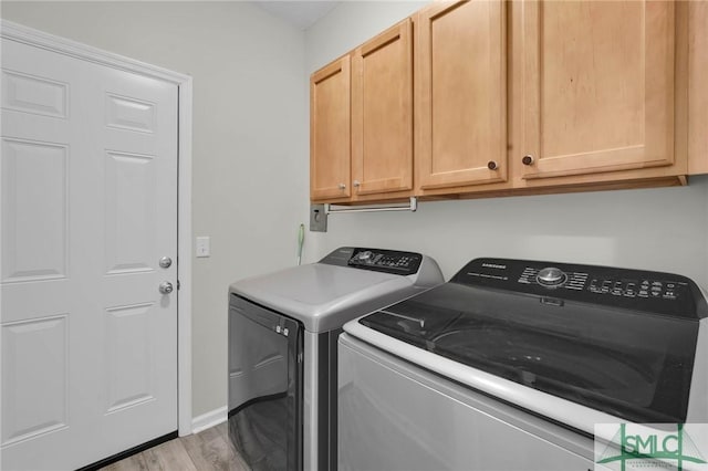 laundry area featuring cabinet space, washing machine and dryer, baseboards, and wood finished floors
