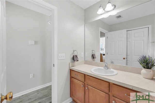 bathroom featuring visible vents, baseboards, wood finished floors, and vanity
