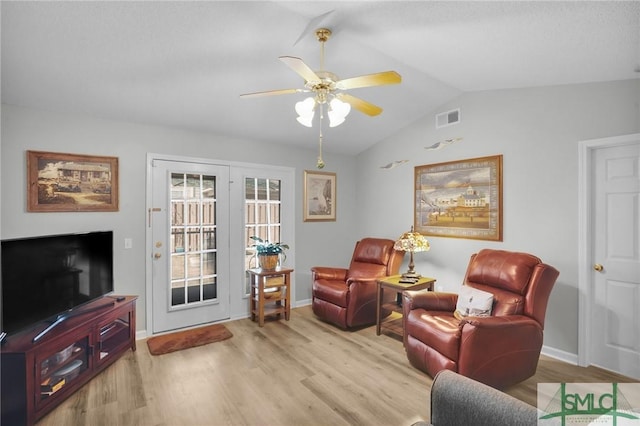 living area featuring a ceiling fan, wood finished floors, visible vents, baseboards, and lofted ceiling