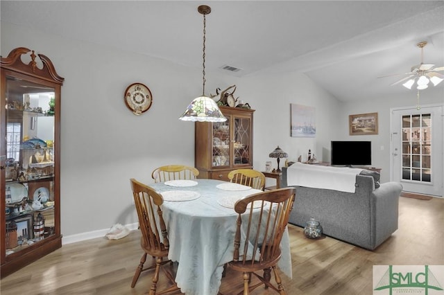 dining room with light wood finished floors, visible vents, a ceiling fan, and lofted ceiling