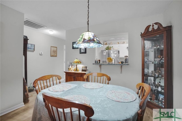 dining room with visible vents, baseboards, and light wood finished floors