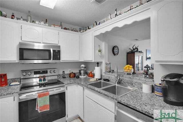 kitchen featuring visible vents, appliances with stainless steel finishes, a textured ceiling, white cabinetry, and a sink