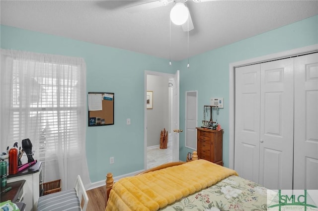 bedroom featuring a ceiling fan, a textured ceiling, wood finished floors, a closet, and baseboards