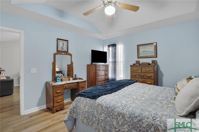 bedroom featuring a ceiling fan, a raised ceiling, baseboards, and light wood-type flooring
