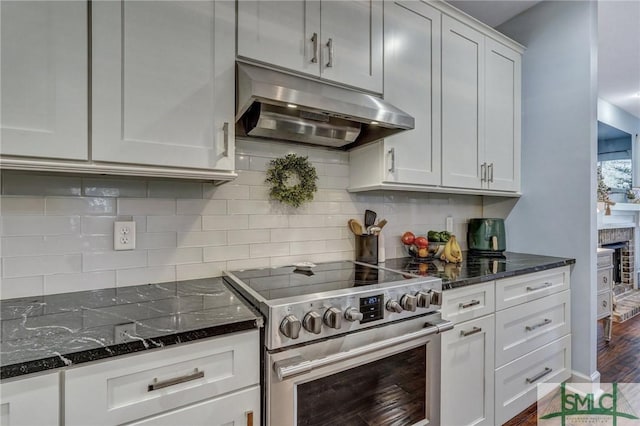 kitchen with stainless steel range with electric stovetop, under cabinet range hood, decorative backsplash, and dark stone counters