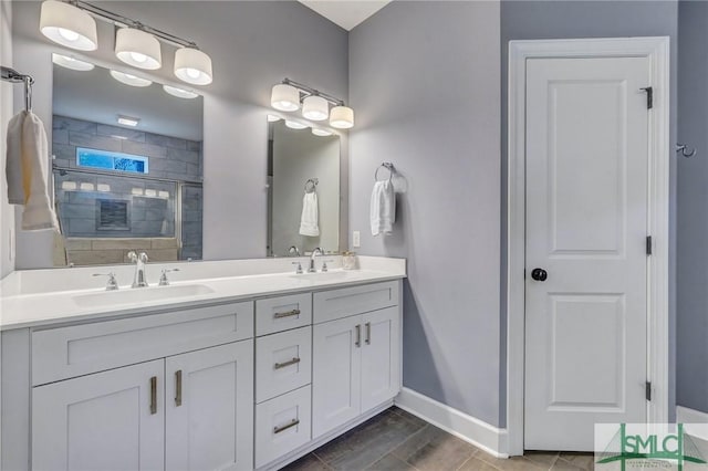 bathroom featuring double vanity, a sink, a shower stall, and baseboards