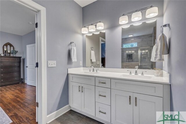 full bathroom with double vanity, a sink, a shower stall, and baseboards