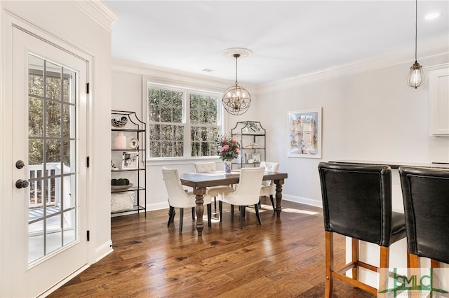 dining area featuring crown molding, dark wood-type flooring, baseboards, and a chandelier
