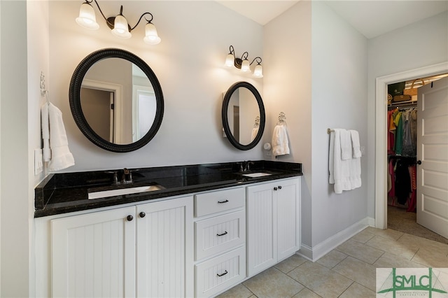 bathroom featuring double vanity, a spacious closet, baseboards, and tile patterned flooring