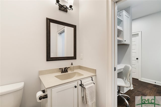 half bathroom with toilet, vanity, and wood finished floors