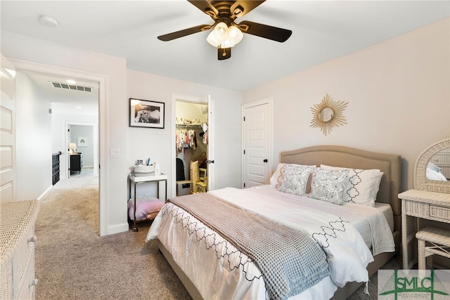 carpeted bedroom with a walk in closet, ceiling fan, a closet, and baseboards