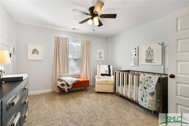 carpeted bedroom featuring baseboards, a nursery area, and a ceiling fan