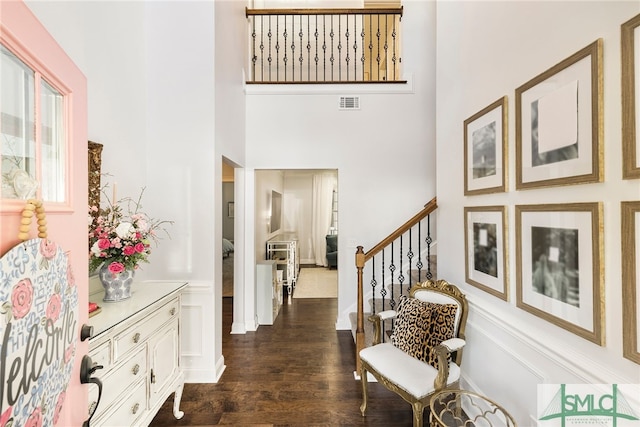 entrance foyer featuring a towering ceiling, dark wood-type flooring, and stairs
