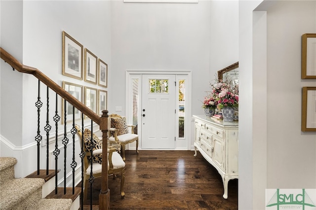 entrance foyer featuring dark wood-type flooring, stairs, and a towering ceiling