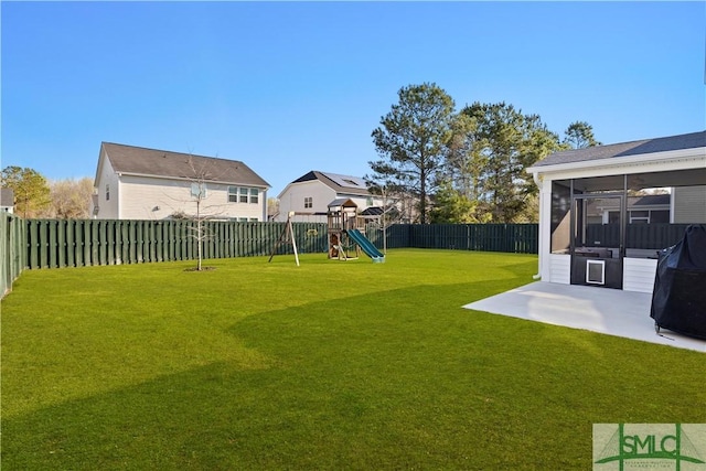 view of yard with a patio, a playground, a fenced backyard, and a sunroom