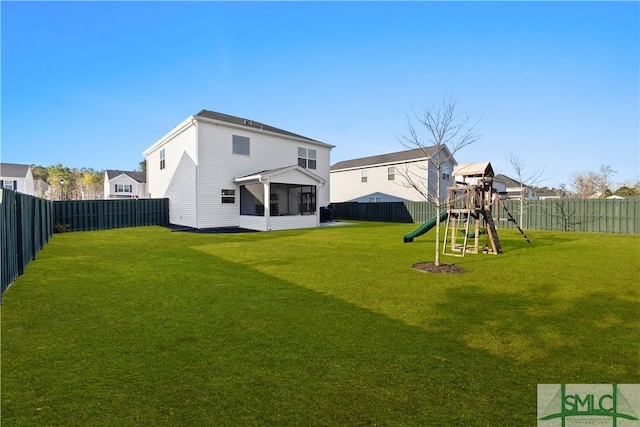 back of house with a lawn, a playground, a fenced backyard, and a sunroom