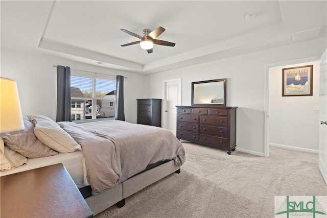 bedroom featuring a tray ceiling, baseboards, carpet, and a ceiling fan