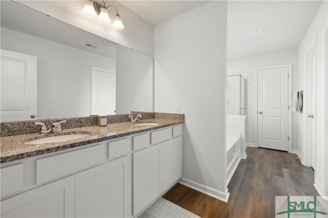 bathroom featuring double vanity, wood finished floors, and a sink