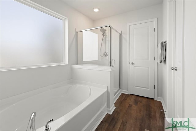 full bath with baseboards, wood finished floors, a garden tub, and a stall shower