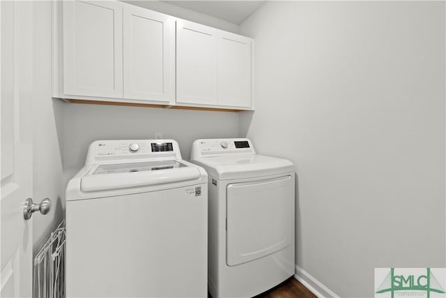 washroom with cabinet space, washing machine and dryer, and baseboards