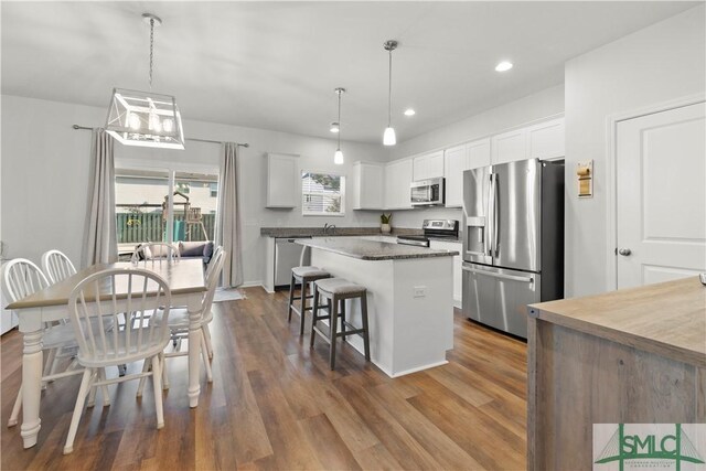 kitchen with stainless steel appliances, a kitchen bar, a kitchen island, and white cabinetry