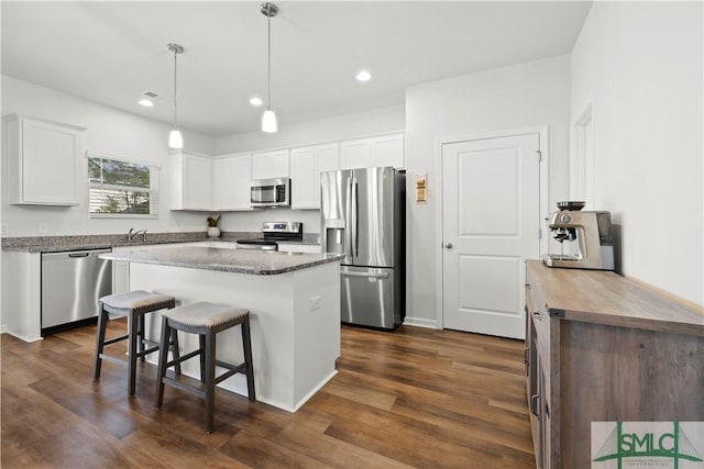 kitchen with white cabinetry, appliances with stainless steel finishes, a breakfast bar area, and dark wood-type flooring