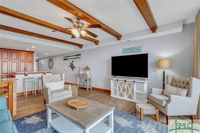 living area featuring wood finished floors, baseboards, beam ceiling, and ceiling fan