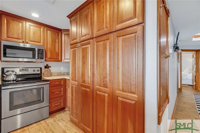 kitchen featuring light wood-type flooring, appliances with stainless steel finishes, and brown cabinetry