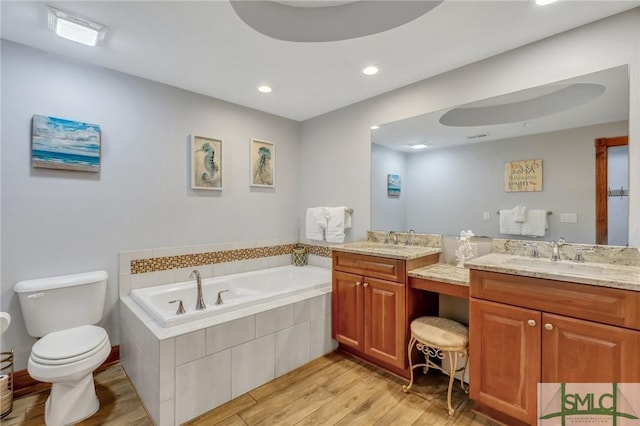 bathroom with vanity, wood finished floors, recessed lighting, a garden tub, and toilet