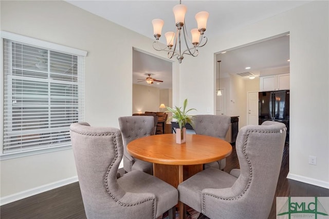 dining area with ceiling fan with notable chandelier, dark wood-style flooring, and baseboards