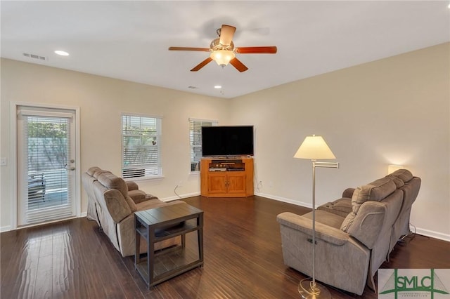 living room with baseboards, visible vents, ceiling fan, and dark wood-style floors