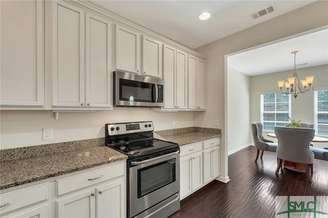 kitchen with visible vents, stainless steel appliances, a chandelier, dark wood-style floors, and stone counters