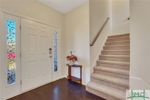 foyer entrance featuring dark wood-style floors, stairs, and baseboards