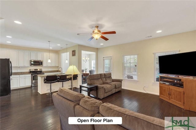 living room with dark wood-type flooring, visible vents, recessed lighting, and ceiling fan with notable chandelier