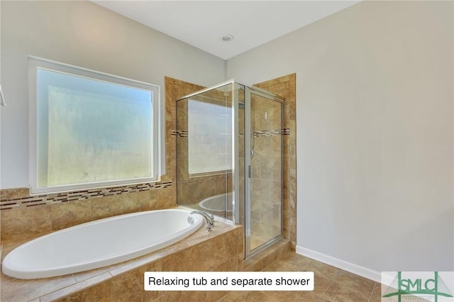 full bathroom featuring tile patterned floors, a bath, a stall shower, and baseboards