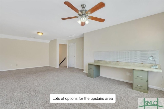 unfurnished office featuring built in study area, ceiling fan, light carpet, and baseboards