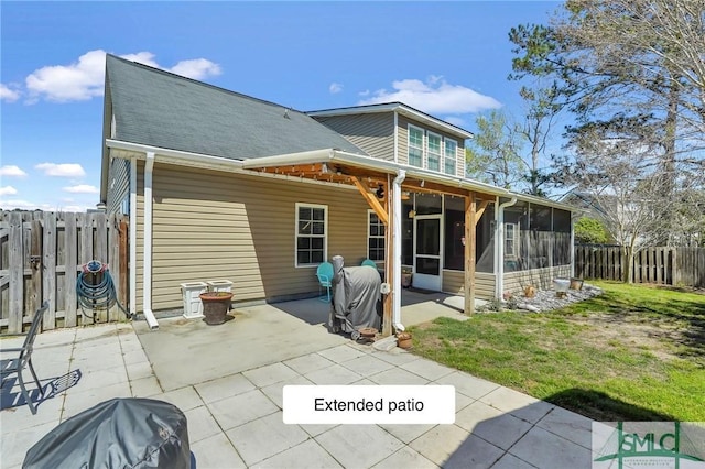 rear view of property with a fenced backyard, a sunroom, roof with shingles, a patio area, and a lawn