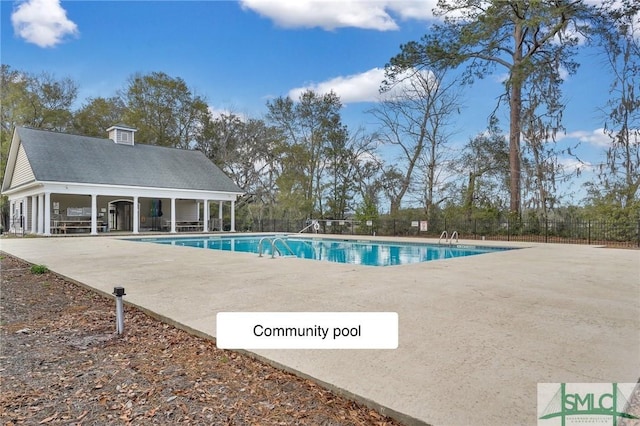 community pool with a patio area and fence