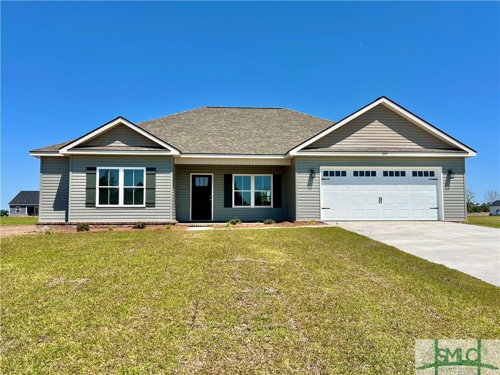 view of front of property with a front yard, concrete driveway, a garage, and roof with shingles