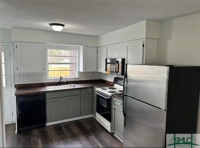 kitchen featuring gray cabinets, a sink, dark wood finished floors, dark countertops, and black appliances